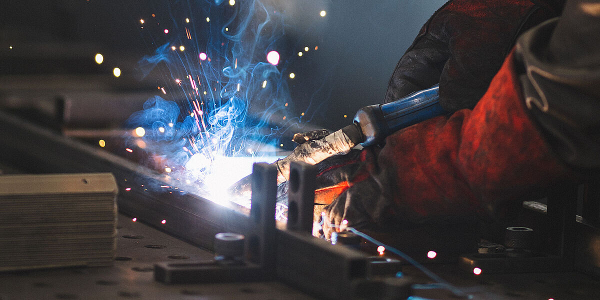 Luftgetragene Partikel am Arbeitsplatz: Schweißer schleifen und schweißen Metallstäbe
