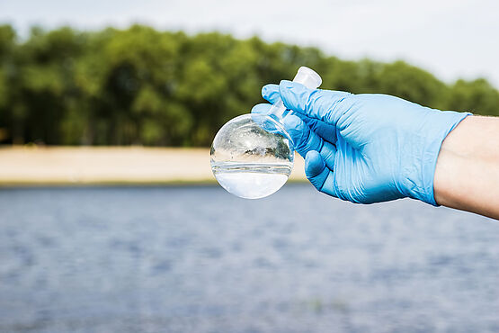 WESSLING Probenehmer hält Wasserprobe in der Hand - Analytik und Beratungsdienstleistungen laufen bei WESSLING Hand in Hand.